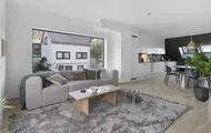 Bilde av stue med sofa, bord, stort teppe og stort vindu fra boligprosjektet Saras Hage i Tromsø