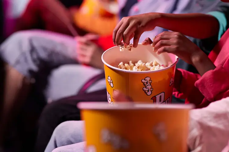 en gruppe venner som deler popkorn med hverandre på kino