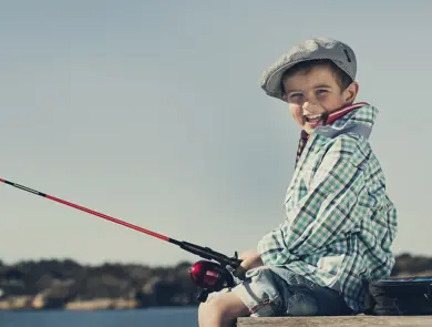 gutt som sitter på brygga og fisker