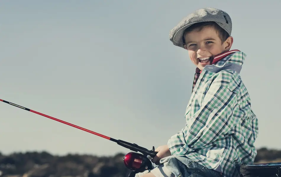 gutt som sitter på brygga og fisker