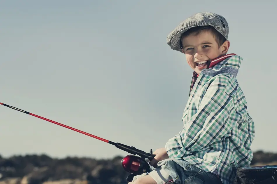 gutt som sitter på brygga og fisker