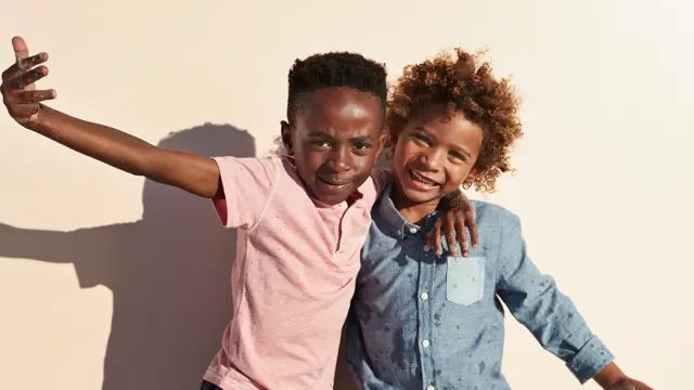 Children having joyful interaction, shot on a blue solid background on the beach in full sun