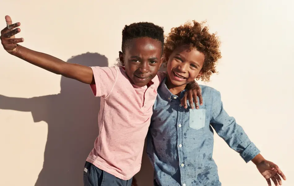 Children having joyful interaction, shot on a blue solid background on the beach in full sun