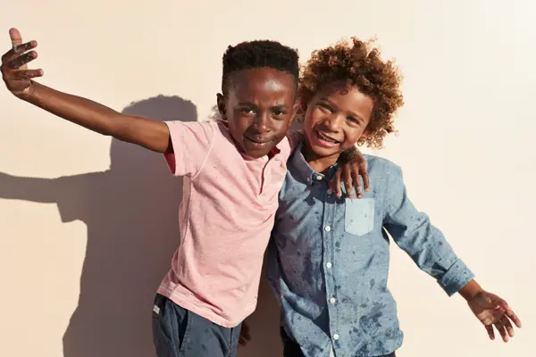 Children having joyful interaction, shot on a blue solid background on the beach in full sun