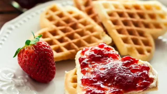 Vaffelhjerter på hvit tallerken med jordbærsyltetøy på