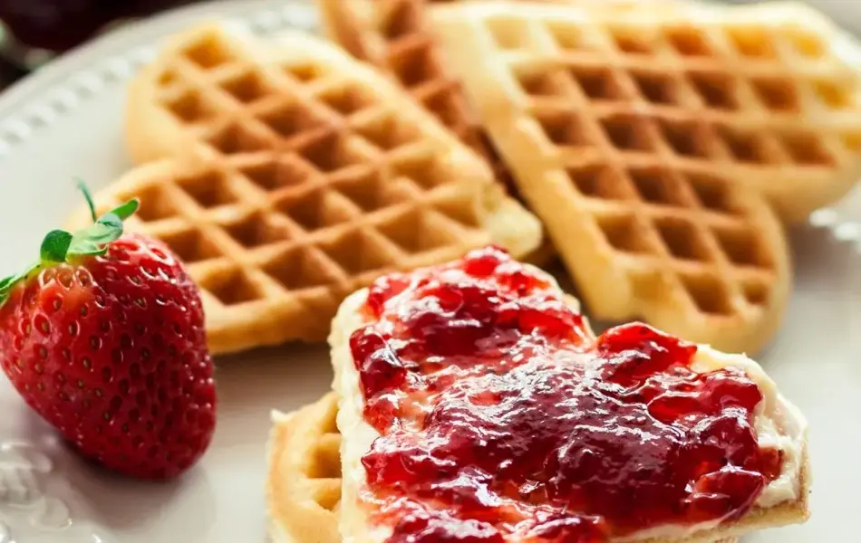 Vaffelhjerter på hvit tallerken med jordbærsyltetøy på