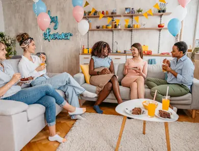 Beautiful young pregnant black woman having a baby shower with friends at home.