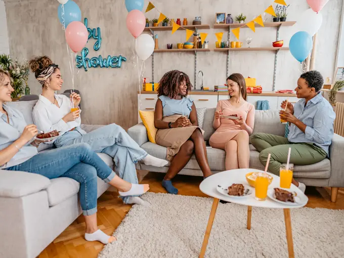 Beautiful young pregnant black woman having a baby shower with friends at home.