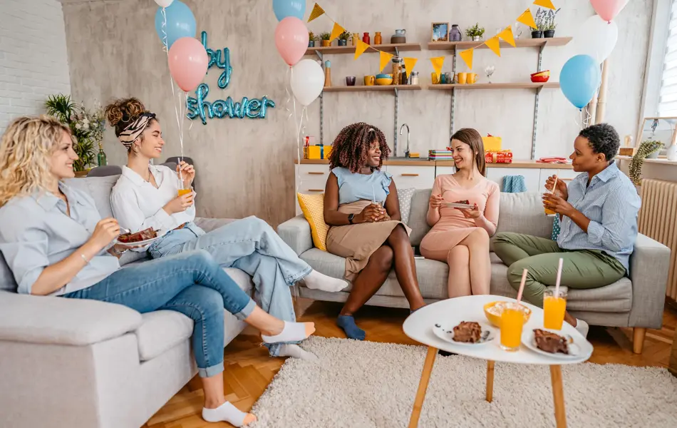 Beautiful young pregnant black woman having a baby shower with friends at home.