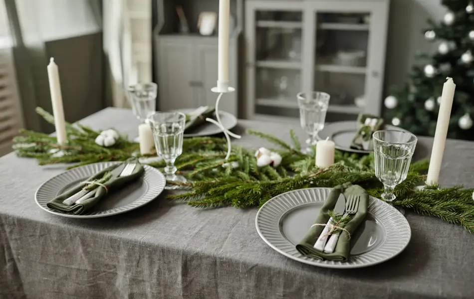 High angle background image of dining room table decorated for Christmas with fir tree branches and candles, copy space