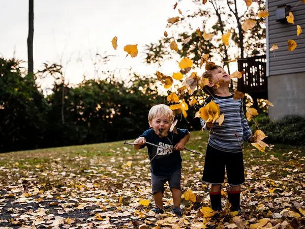 To gutter leker i høstløvet. Foto.