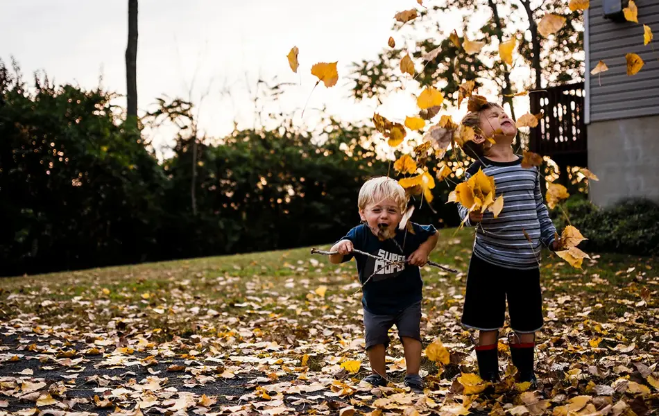 To gutter leker i høstløvet. Foto.