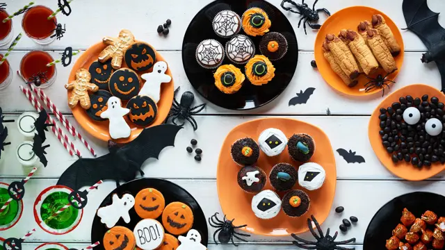 High angle view of Halloween cookies, candies, cupcakes, drinks on decorated table
