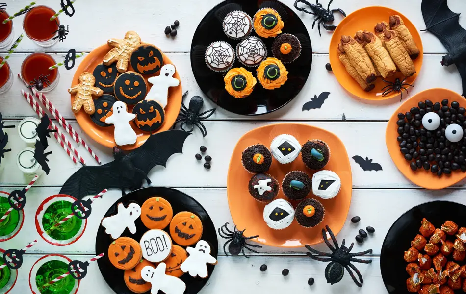 High angle view of Halloween cookies, candies, cupcakes, drinks on decorated table
