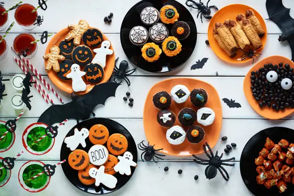 High angle view of Halloween cookies, candies, cupcakes, drinks on decorated table