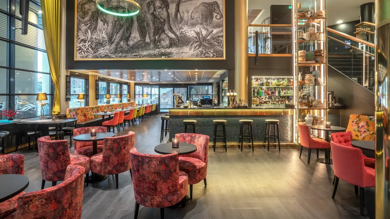 Bar, svart gulv, svarte bord, rosa stoler, vinduer langs hele veggen.