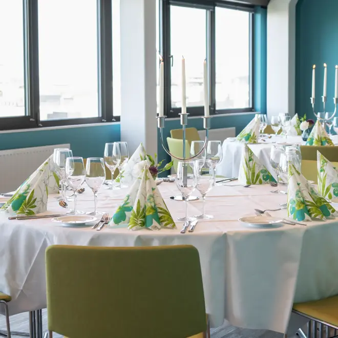 Dekkete bord med hvite duker og fargerike servietter i selskapslokale Lysefjord, med store vinduer, på Thon Hotel Maritim