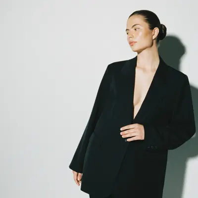 En kvinne i en sort dress foran en grå vegg