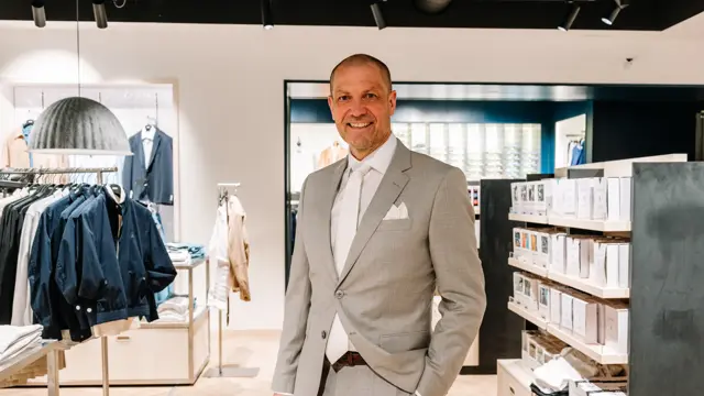 mann i dress står i butikk