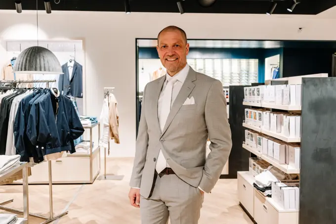 mann i dress står i butikk