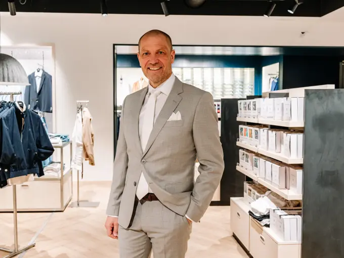 mann i dress står i butikk