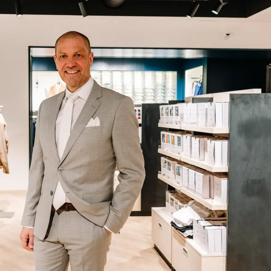 mann i dress står i butikk