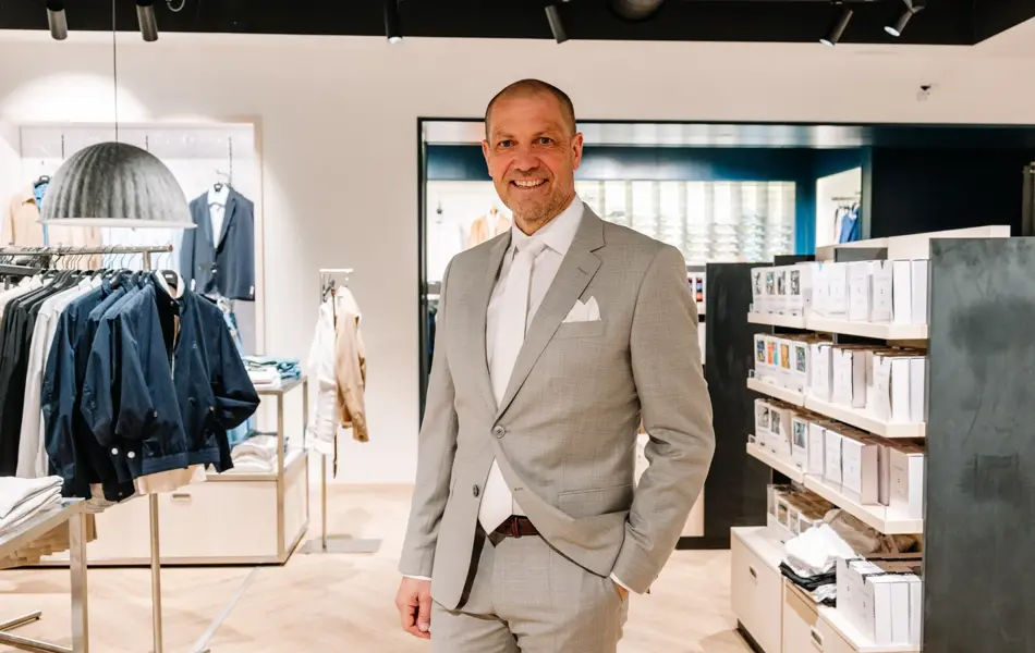 mann i dress står i butikk