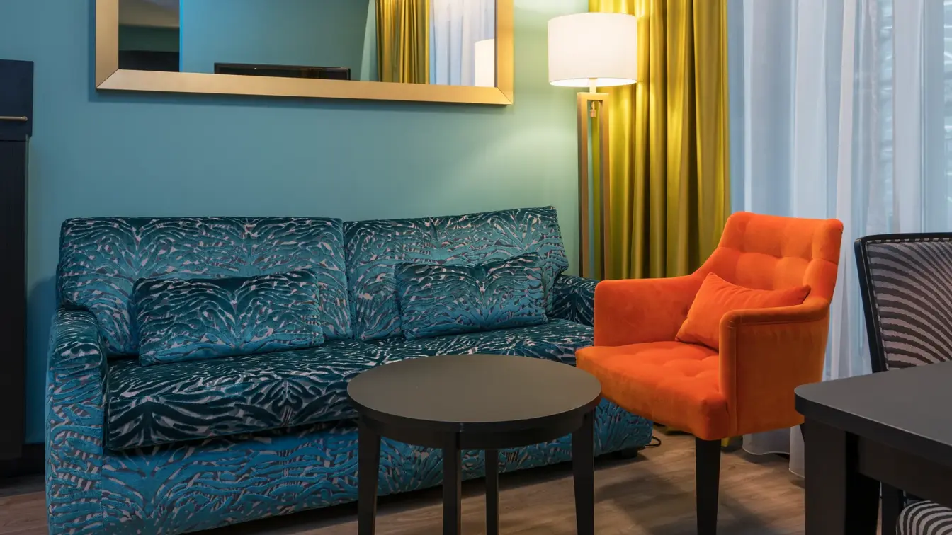 Blå sofa, orange lenestol og skrivebord i Superiorom på Thon Hotel Linne