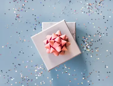 White silver gift boxes with pink bow on blue background in trendy flat lay composition with shiny glitters.