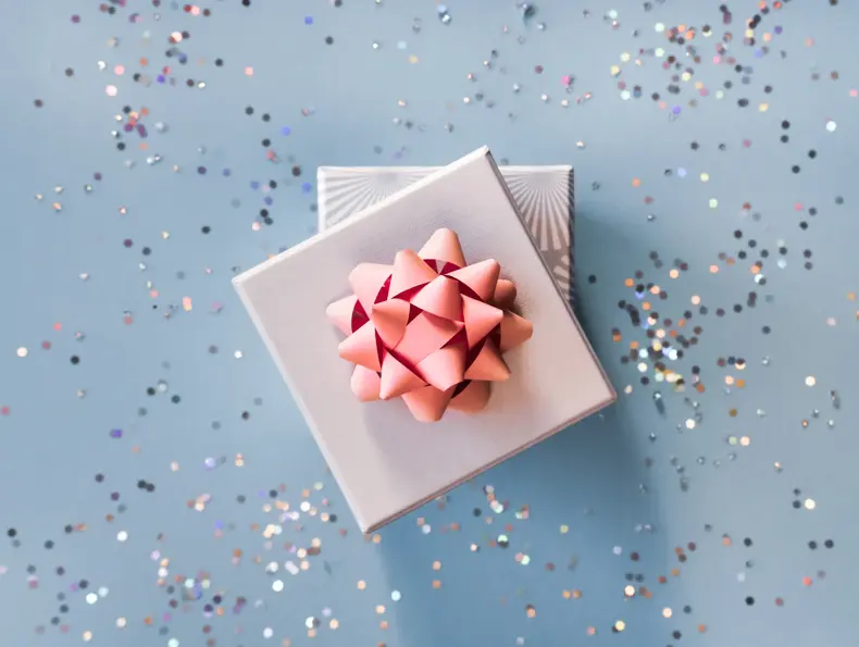 White silver gift boxes with pink bow on blue background in trendy flat lay composition with shiny glitters.