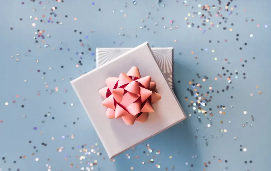 White silver gift boxes with pink bow on blue background in trendy flat lay composition with shiny glitters.