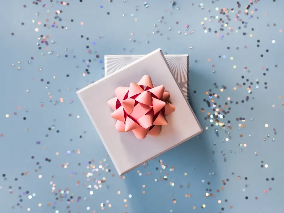 White silver gift boxes with pink bow on blue background in trendy flat lay composition with shiny glitters.