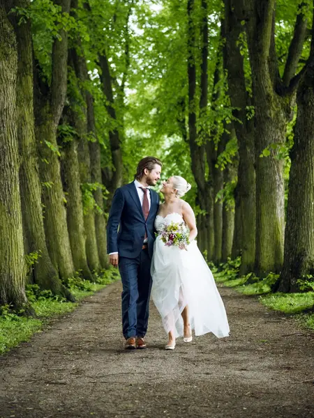 Brudebilde av forelsket nygift par omgitt av trær 