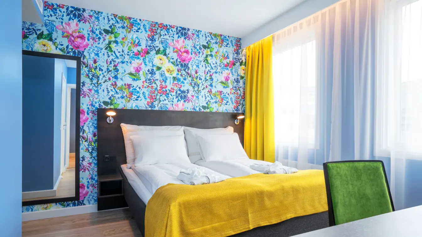 Dobbeltseng, blomstrete tapet, speil og skrivebord i suite på Thon Hotel Moldefjord