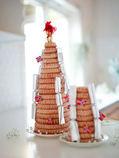 To kransekaker i ulike størrelse pyntet med flagg og bonbons på et bord