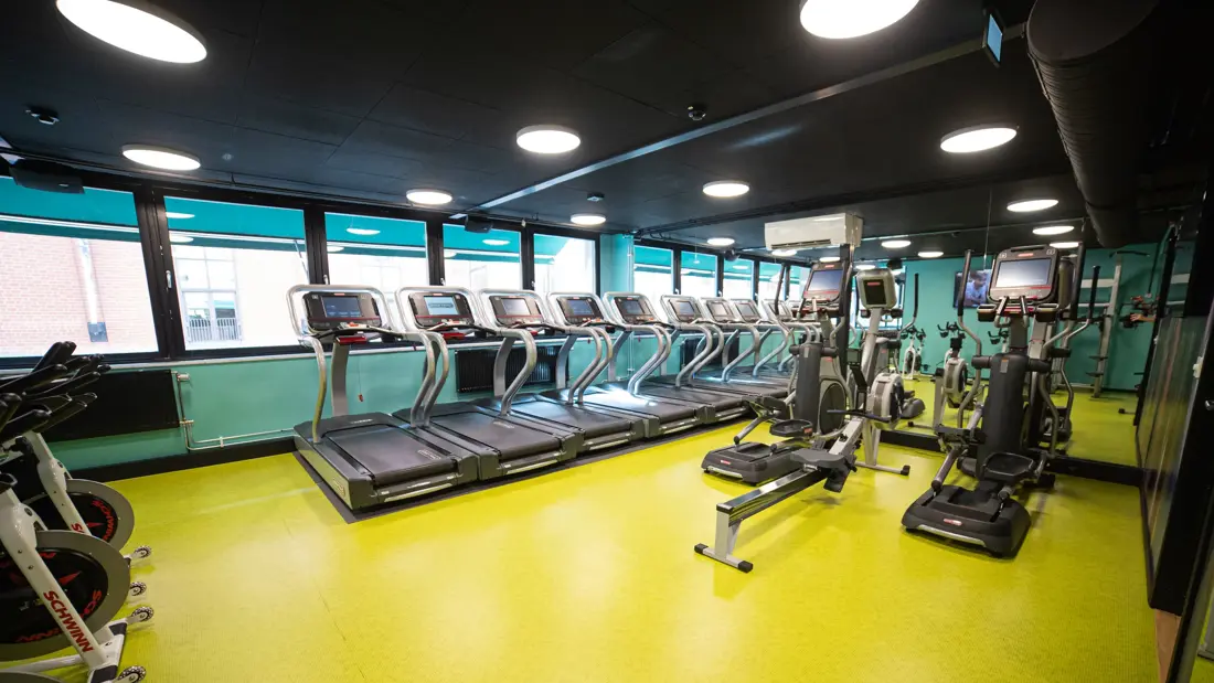 Treningsrom med vinduer, tredemøller og romaskin