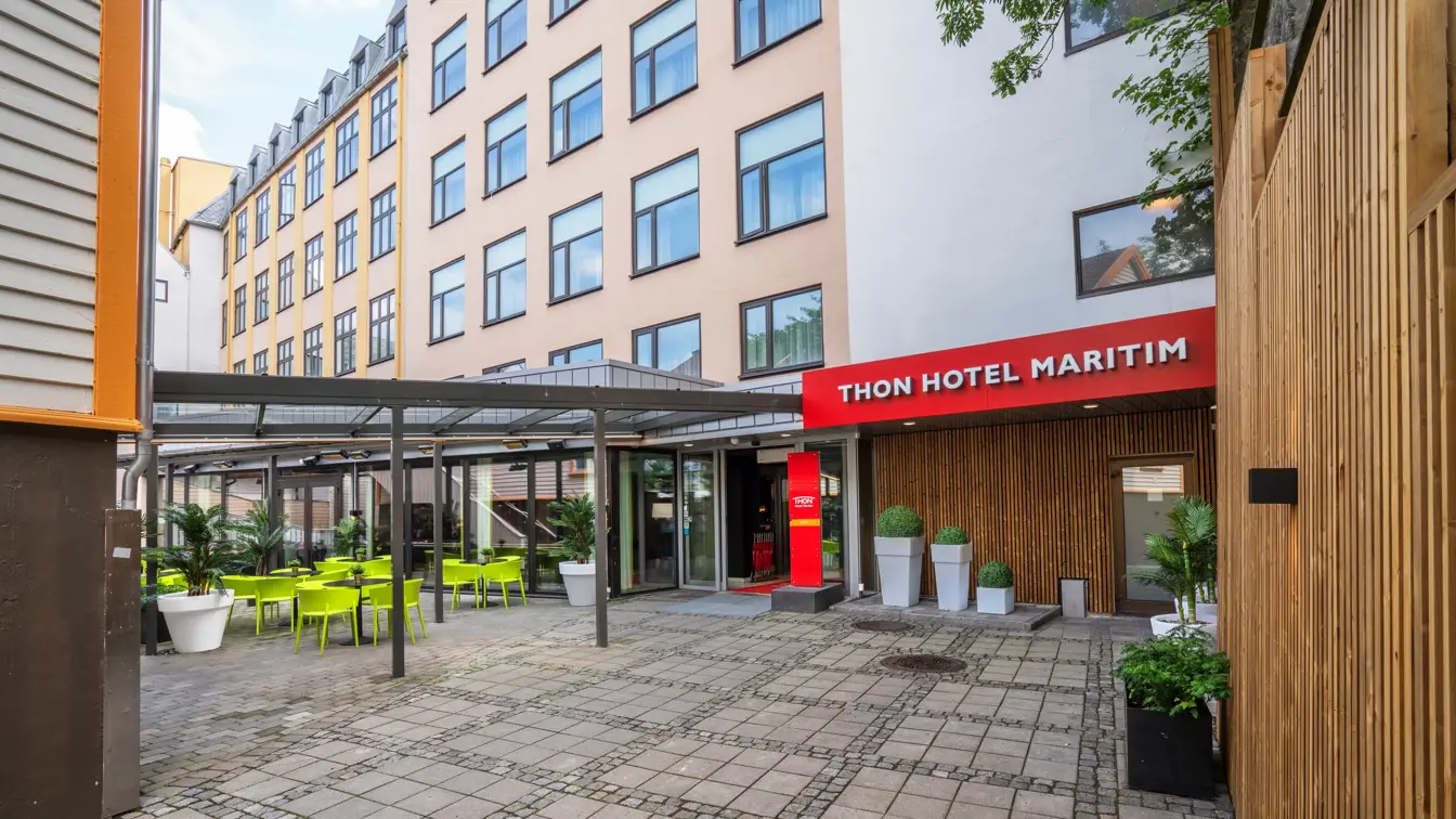 Fasade med rød Thon Hotel Maritim skilt og uteområde med sittegrupper på Thon Hotel Maritim.