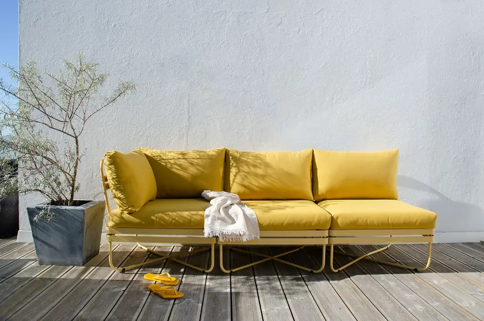 Gull sofa på platt med en grønn plante ved siden av