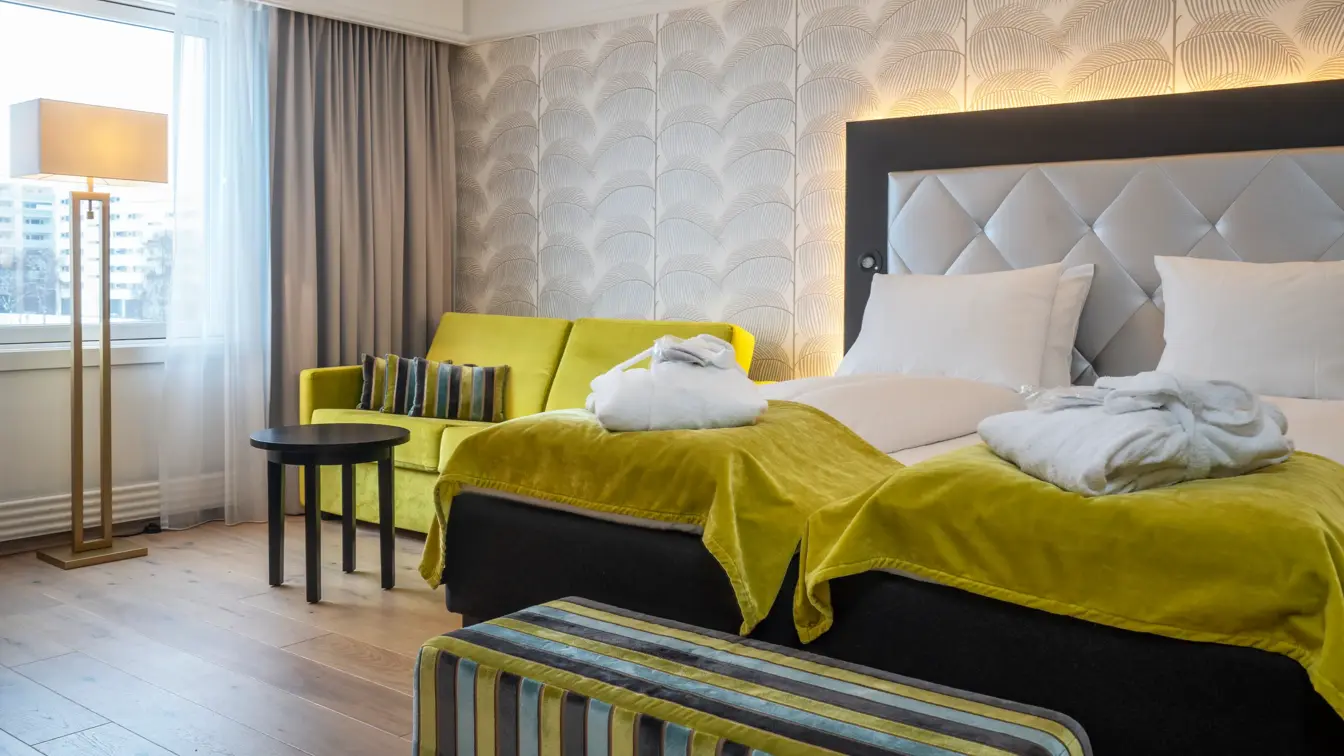 Dobbeltseng, vindu, gul sofa, beige tapet,morgenkåper