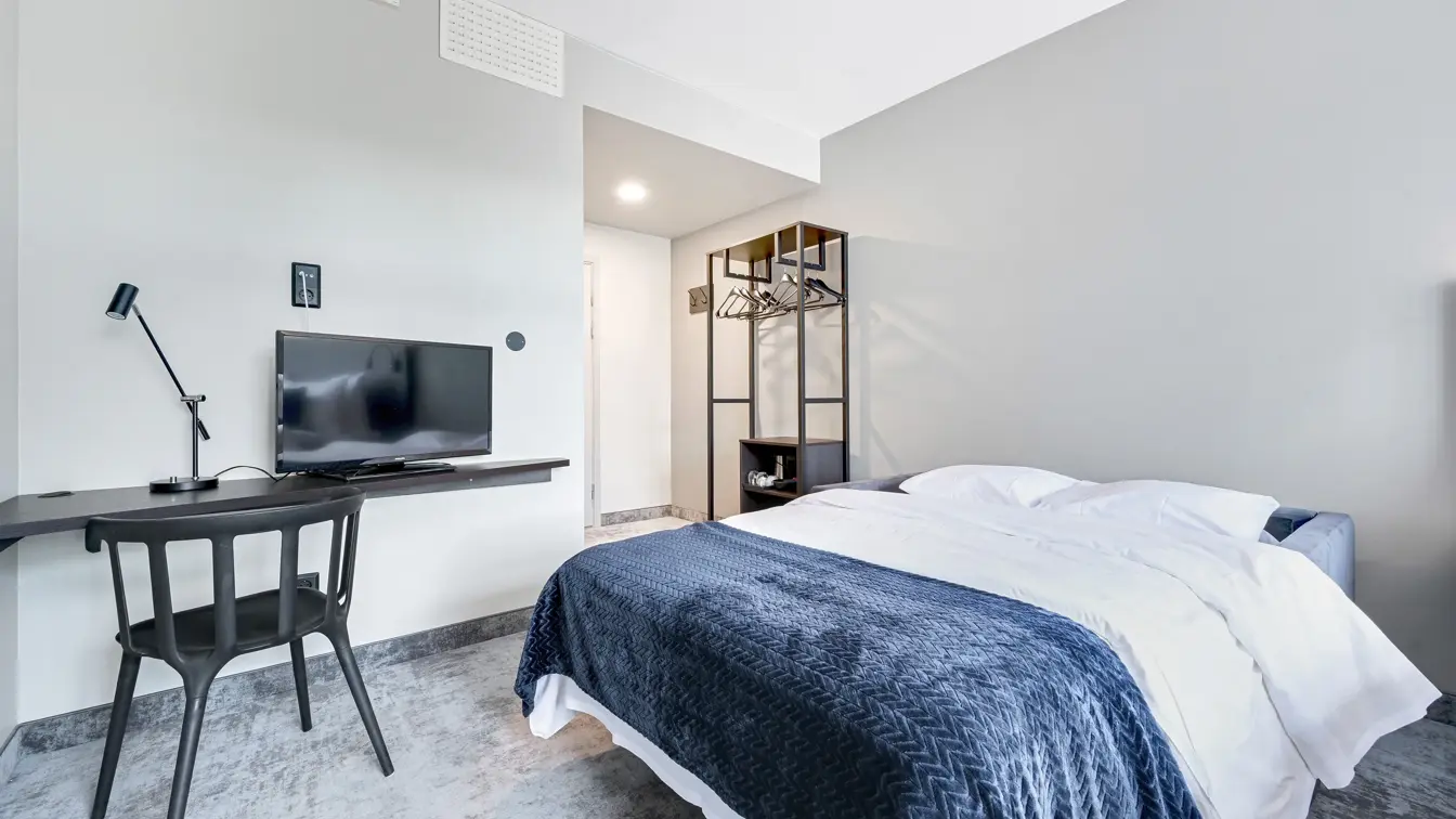 Dobbeltseng, hvite vegger, skrivebord, TV, stol