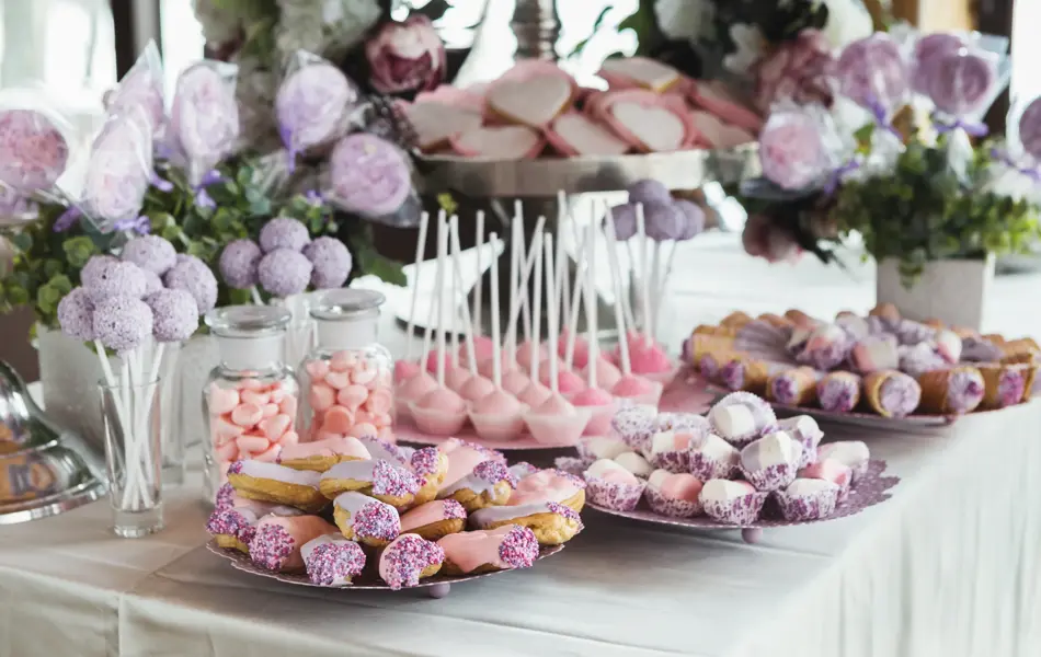 Pink candy bar for holiday celebration. Sweet buffet for birthday party or wedding. Desserts assortment against wooden background, catering concept