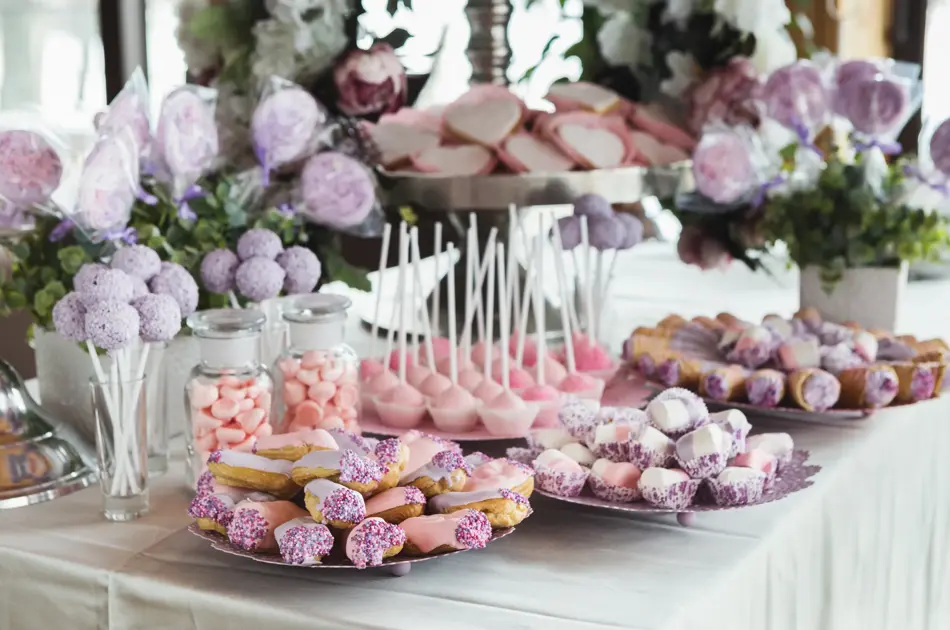 Pink candy bar for holiday celebration. Sweet buffet for birthday party or wedding. Desserts assortment against wooden background, catering concept