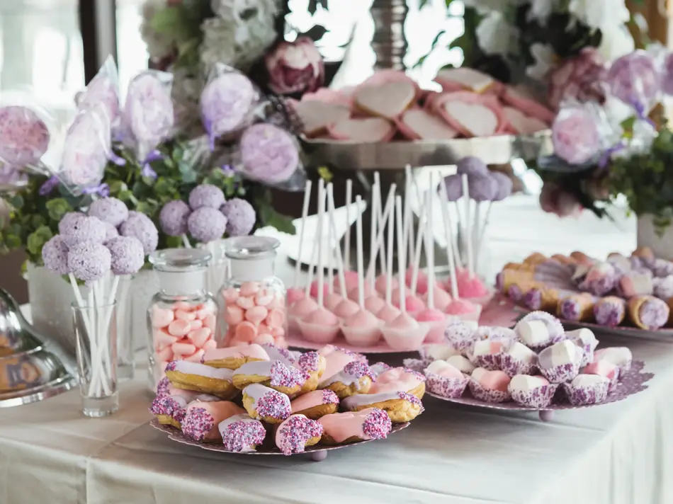 Pink candy bar for holiday celebration. Sweet buffet for birthday party or wedding. Desserts assortment against wooden background, catering concept