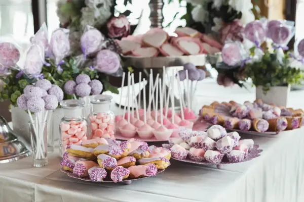 Pink candy bar for holiday celebration. Sweet buffet for birthday party or wedding. Desserts assortment against wooden background, catering concept