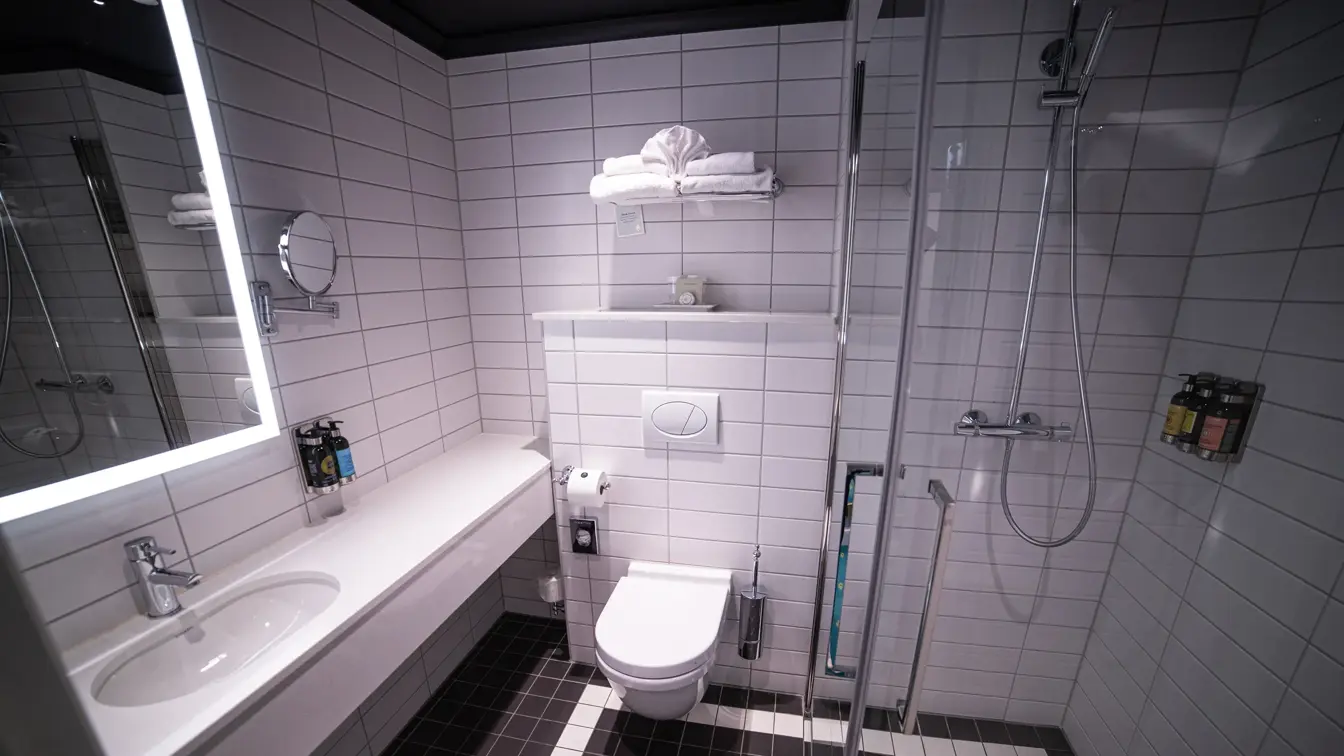 Bad med vegghengt toalett, servant med speilskap og dusjhjørne