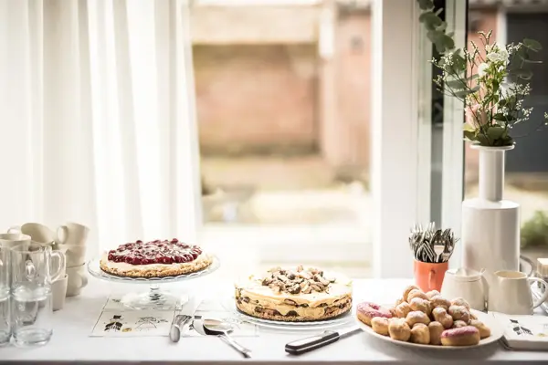 Utsnitt av kakebord med hvit duk og tre ulike kaker. Foto til artikkel om ting å huske på når du skal arrangere konfirmasjon.