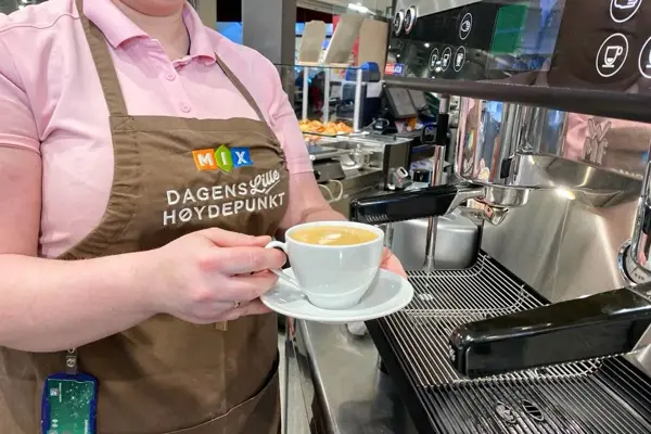 Overkropp dame med barista maskin og kaffekopp
