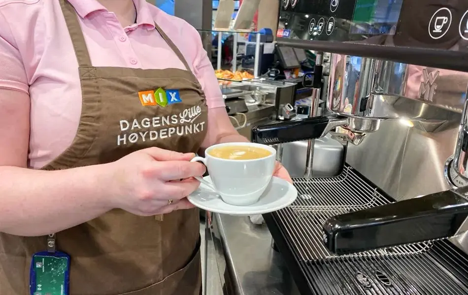 Overkropp dame med barista maskin og kaffekopp