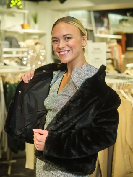 ansatt hos vero moda viser frem svart pelsjakke og grå kjole