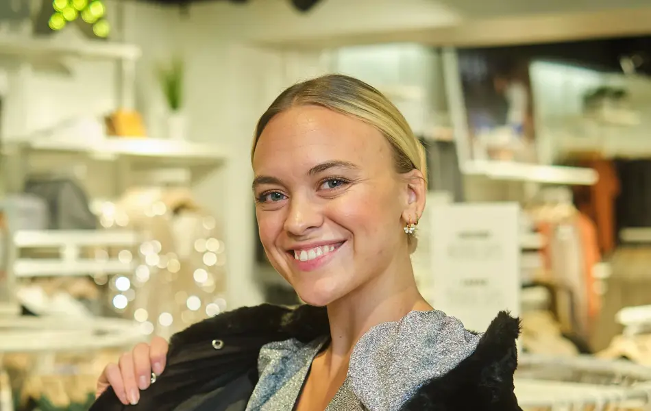 ansatt hos vero moda viser frem svart pelsjakke og grå kjole